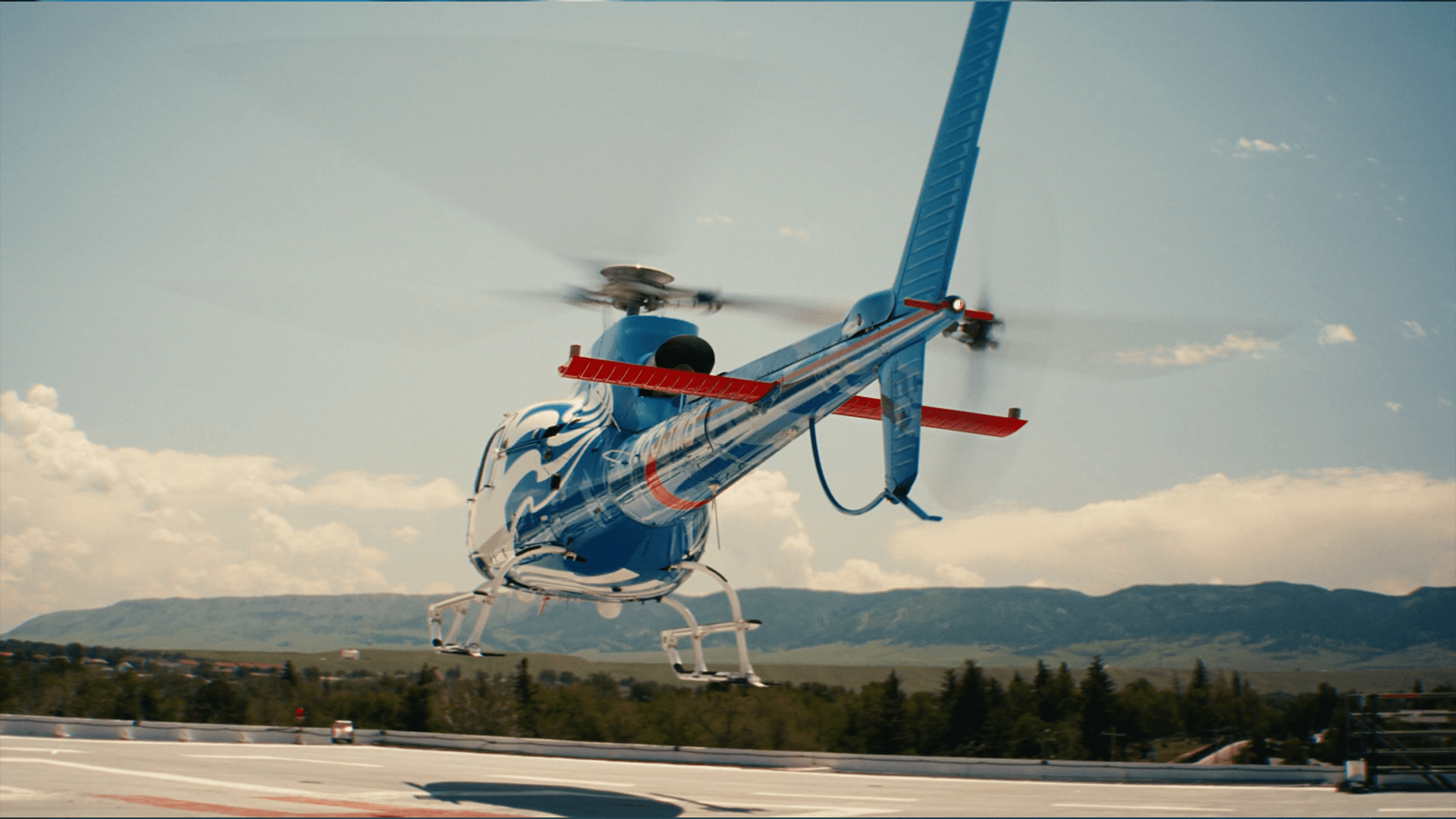 A Banner Health air-ambulance helicopter lifting off a rooftop helipad, Arizona foothills behind it